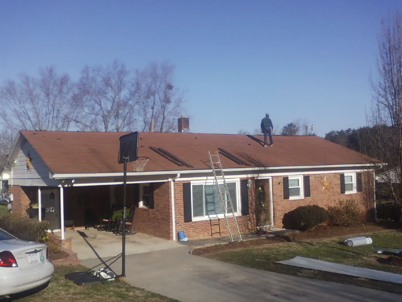 Roofer stripping a shingle roof on a brick ranch before metal panels in Fresno