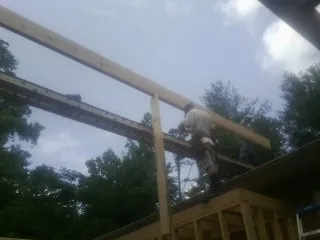 Carpenter setting a ridge beam over a new addition frame — Ice Dam Removal by Roofing Brothers in Fresno