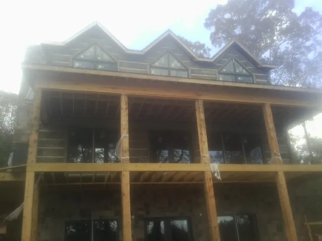 Dormers and porch framing on a large log home under construction — Roof Coating work by our crew in Fresno