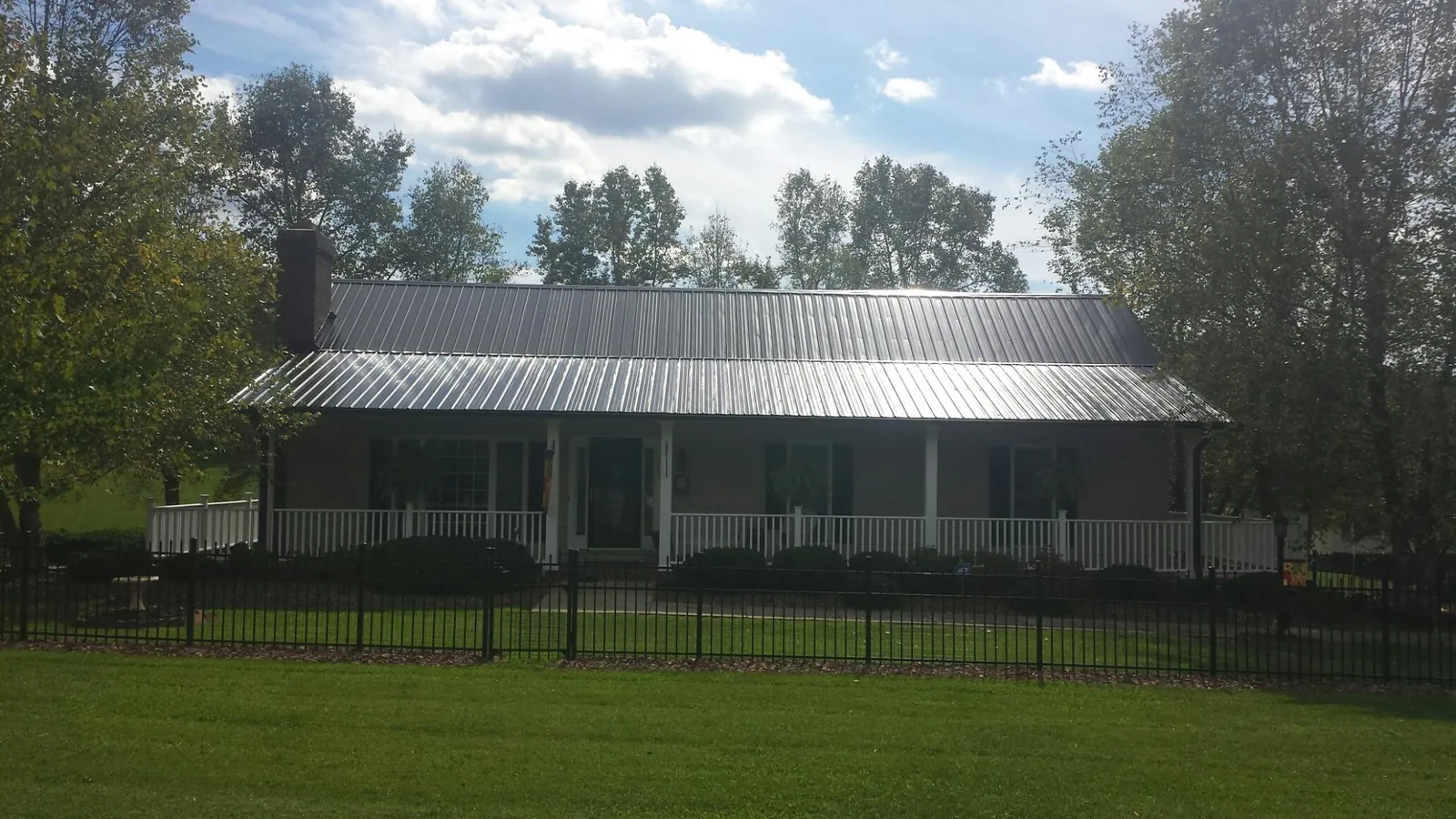 Gray metal roof on a brick ranch with a full width front porch — Gutter Guard Installation work by our crew in Fresno