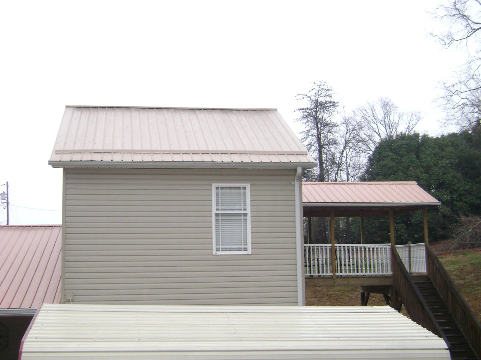 Tan metal roofs on a two story addition and attached porch, from a Roof Replacement job in Fresno